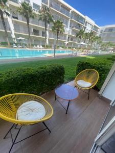 twee gele stoelen en een tafel naast een zwembad bij Kettani Bouznika Hind in Bouznika