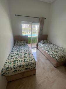 twee bedden in een kamer met een raam bij Kettani Bouznika Hind in Bouznika