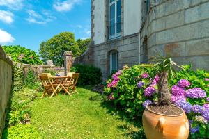 a yard with a table and chairs and flowers at Appartement au Château de Locqueran - Mer in Plouhinec +4 photos