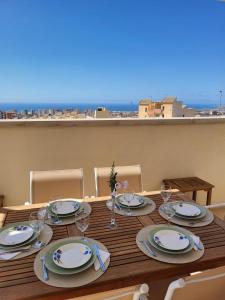 a table with plates and wine glasses on a balcony at Casa Las Colinas in Roquetas de Mar