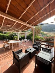 eine Terrasse mit Stühlen und Tischen und einem Holzdach in der Unterkunft Like Home Calamazzo di Sciacca in Scopello