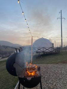 a bbq grill with flames and a tent in the background at Глемпінг Хатинка на полонині in Krivopolʼye