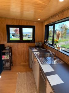 a kitchen with a sink and two windows at Ohingaiti Farm Cottage in Ohingaiti