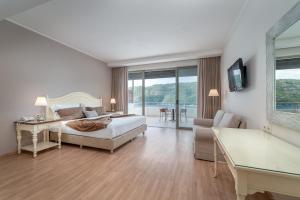 a bedroom with a bed and a desk and a couch at San Nicolas Resort Hotel in Mikros Gialos