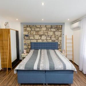 a blue bed in a room with a stone wall at Silver Apartments in Bogács