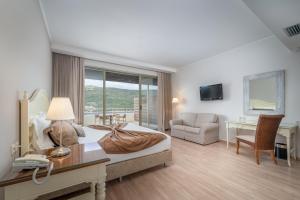 a hotel room with a bed and a desk and a couch at San Nicolas Resort Hotel in Mikros Gialos