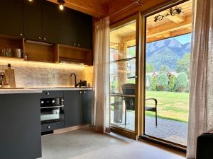 a kitchen with black cabinets and a large glass window at Domki Trzy Korony in Sromowce Niżne