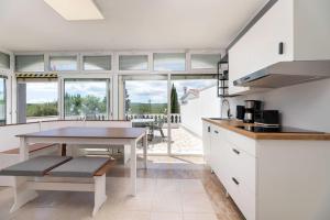 una cocina con armarios blancos y una mesa con comedor. en Apartments Maria, en Šilo