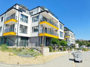 a large white building with yellow balconies on a street at Boho and More in Sozopol