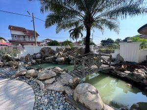 a bridge over a pond with rocks and a palm tree at DeGarden House Bangi in Kajang