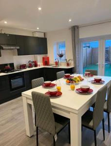 una cocina con una mesa blanca con sillas y bebidas. en JB Stays Therapia, en Hackbridge