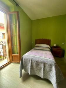 a green bedroom with a bed and a window at La Casona de Ardines in Arenas de Cabrales