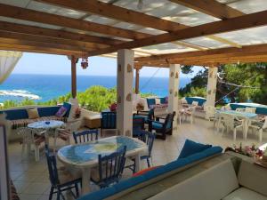 a patio with tables and chairs and the ocean at Kocheilas Studios in Gialiskari
