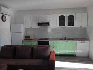 a kitchen with green cabinets and a couch at Apartman Neda in Sveti Ivan Dobrinjski +9 photos