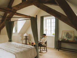a woman sitting in a chair in a bedroom at Bellevigne Bourgogne in Chambolle-Musigny