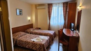 a hotel room with two beds and a desk at Caprice Family Hotel in Varna City