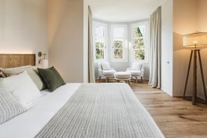 Un dormitorio con una gran cama blanca y dos ventanas. en Hotel Rural Sant Patrici, en Ferreries