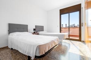 two beds in a white room with a large window at La Plana in Creixell +16 photos