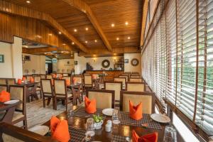 a restaurant with tables and chairs with orange pillows at Summit Norling Resort & Spa in Gangtok