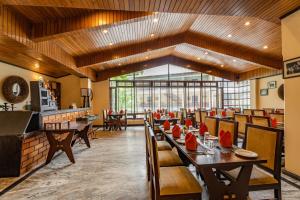 a restaurant with wooden ceilings and tables and chairs at Summit Norling Resort & Spa in Gangtok