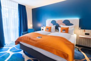 a bedroom with a large bed with an orange blanket at Holiday Inn - the niu, Stream Mönchengladbach by IHG in Mönchengladbach