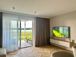a living room with a television and a sliding glass door at MG52 Luksusowy apartament z widokiem na Zalew Zegrzyński in Zegrze Południowe