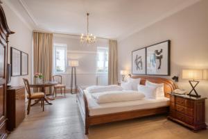 a bedroom with a bed and a desk and a table at Hotel Eisenhut in Rothenburg ob der Tauber