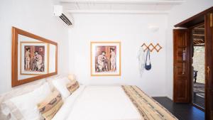 a white room with a bed and paintings on the wall at Lavender Studio in Patmos