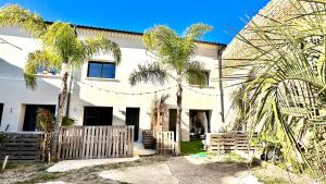 a white house with palm trees in front of it at Les Gîtes de la Chapelle 3 in Vauvert