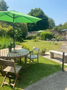 a picnic table with a green umbrella and benches at Coachmans Rest in Sandwich
