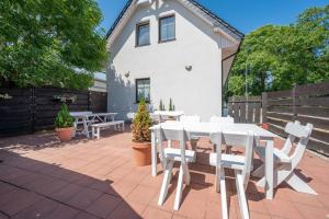a patio with white tables and chairs in front of a house at Pokoje blisko morza Przy Porcie in Darłowo
