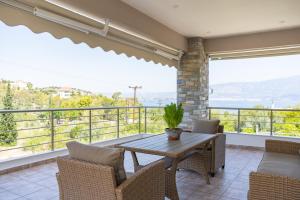 a dining room with a table and chairs on a balcony at Villa Brezza Di Mare - Agios Stefanos Volos in Kritharia