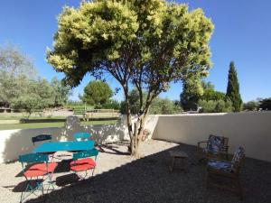 a table and chairs under a tree next to a wall at Le Gîte de Pandore in Arles