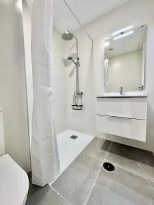 a white bathroom with a shower and a toilet at Sunny Seas Hideaway Apartment in Los Abrigos