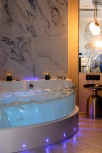 a jacuzzi tub in a room with a marble wall at Apartament LUNA z jacuzzi Premium na Mazurach in Ełk