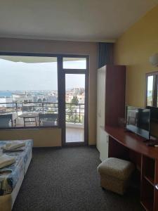 a hotel room with a bed and a desk and a balcony at St. George Guest House in Sveti Vlas