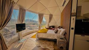 a woman laying on a bed in a room with a large window at Glamping Casas Eco Natura in Cabrais