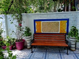 a wooden bench sitting next to a wall with plants at The Coral House Homestay by the Taj in Agra