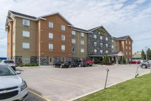 a hotel with cars parked in a parking lot at MainStay Suites Winnipeg in Winnipeg