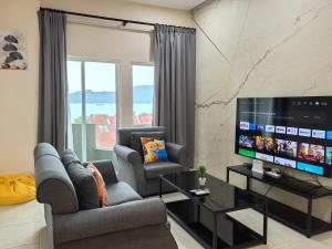 a living room with two chairs and a flat screen tv at Langkawi Simfoni Platinum Suite in Kuah