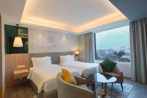 a hotel room with two beds and a couch at Park Inn by Radisson Ayodhya in Ayodhya