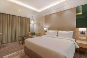 a hotel room with a large bed and a chair at Park Inn by Radisson Ayodhya in Ayodhya
