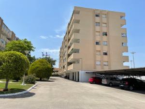a large building with cars parked in a parking lot at Vacaciones en familia Ap Portitxol en Xàbia in Platja de l'Arenal