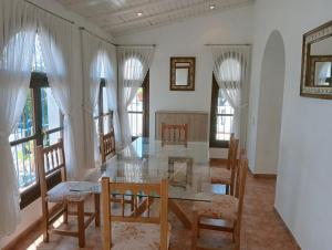 a dining room with a table and chairs and windows at AT Chalet Stella con Piscina Privada in Peniscola