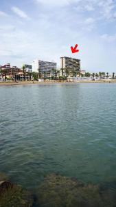 ein großer Wasserkörper mit Strand und Gebäuden in der Unterkunft Apartamento en complejo residencial con piscina in Puebla de Farnals