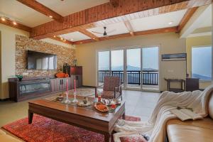 a living room with a couch and a table at SaffronStays Ridgeview Manor, Mukteshwar - 3BHK Villa with Himalayan Views & Verandahs in Mukteshwar