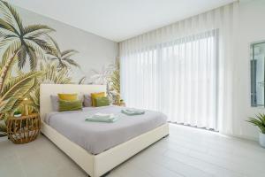 a white bedroom with a white bed with yellow and green pillows at Villa Bianca with jacuzzi and private swimming pool in Mariquiteira +33 photos