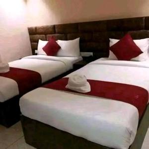 two beds in a hotel room with red and white pillows at Hotel Suramma Pvt. Ltd. in Lumbini