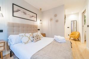 ブルゴスにあるCid Campeador II - Apartamentos Burgos Deluxeの大きな白いベッドと椅子のある寝室