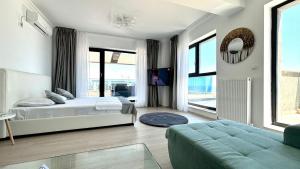 Un dormitorio con una cama y un sofá y ventanas. en North Club Apartments II, en Mamaia 161 fotos más